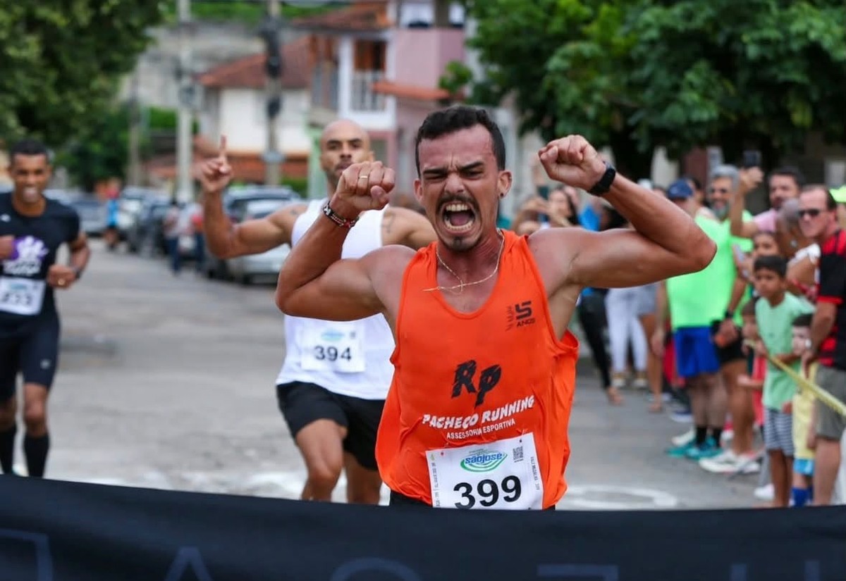Atleta da Pacheco Running cruzando a fita de chegada com raça e regata oficial da equipe